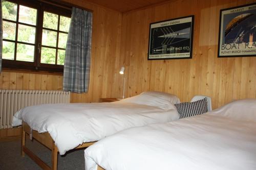 two beds in a room with wooden walls at La Moussiere in Morgins