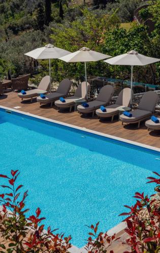 a swimming pool with lounge chairs and umbrellas at Irida Aegean View, Philian Hotels and Resorts in Megali Ammos