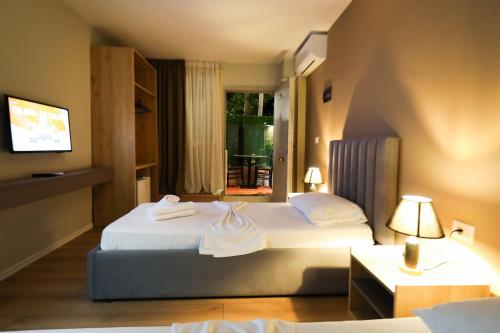 a hotel room with two beds and a television at Hotel HER in Vlorë