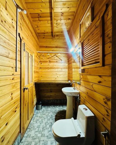 a wooden bathroom with a toilet and a sink at Hotel Inn morjim in Morjim