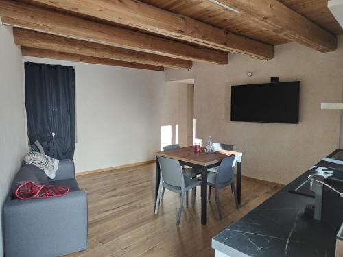 a dining room with a table and chairs and a television at Alloggio Bellavista in Rore