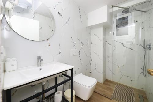 a white bathroom with a sink and a mirror at Hotel HER in Vlorë