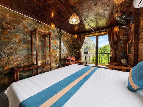 a bedroom with a large bed with a stone wall at Tam Coc Mountain Ecolodge in Ninh Binh