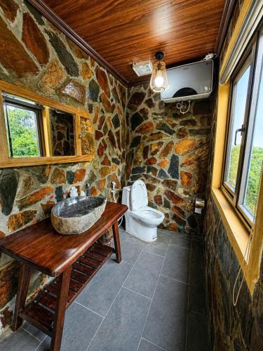 a stone bathroom with a sink and a toilet at Tam Coc Mountain Ecolodge in Ninh Binh