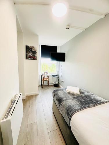 a white bedroom with a bed and a desk at Melrose Abbey Guest House in Liverpool