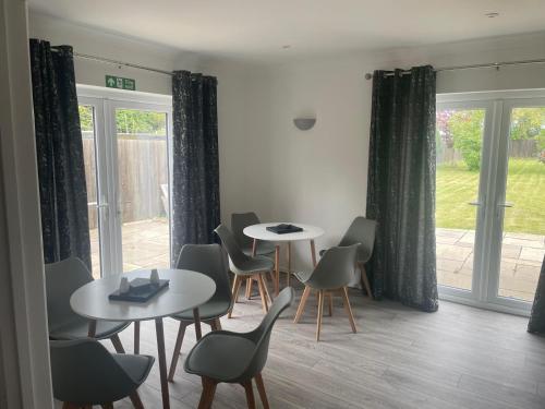 a dining room with tables and chairs and windows at Wilton Manor 79 Wilton road in Feltwell