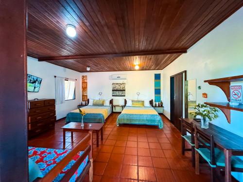 a large room with two beds and a table at Pousada Casa da Edinha in Ilha de Boipeba