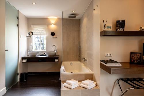 a bathroom with two sinks and a bath tub at 't Ganzenest Restaurant # klein hotel in Rijswijk