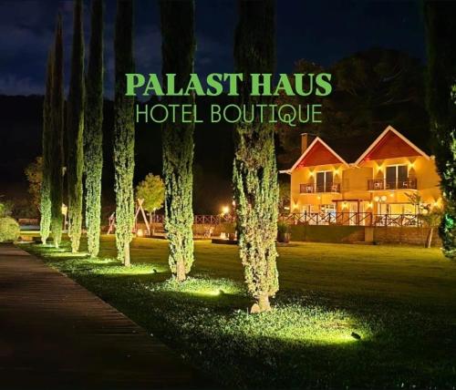 a row of trees in front of a hotel at night at Palast Haus Hotel Boutique in Gramado