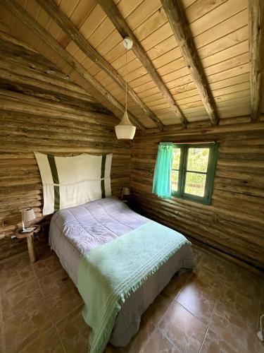 a bedroom with a bed in a log cabin at Cabañas del Mesón in Potrerillos