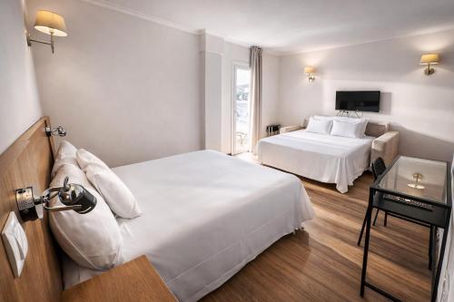 a hotel room with two beds and a television at Nura Santa Ponsa & Spa in Santa Ponsa