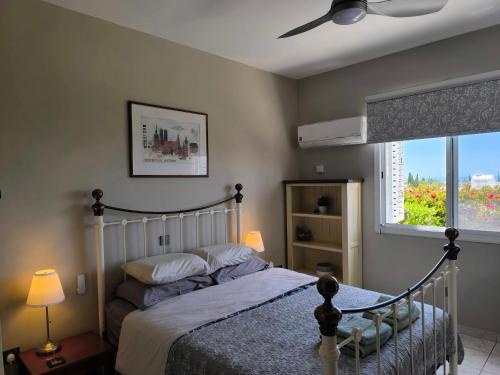 a bedroom with a bed with a fan and a window at Villa Best Holiday Sea View Private Pool near Coral Bay with Garden and BBQ in Peyia