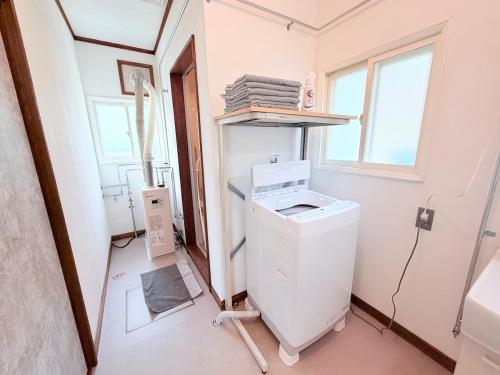 a laundry room with a washing machine and a window at Hokkaido Wander House in Ashibetsu