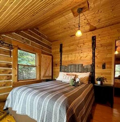 a bedroom with a bed in a wooden cabin at Cedar Gap Hideaway in Indiana in Birdseye