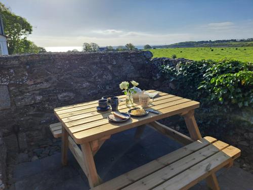 a wooden picnic table with food and flowers on it at Mulberry Cottage in Whithorn