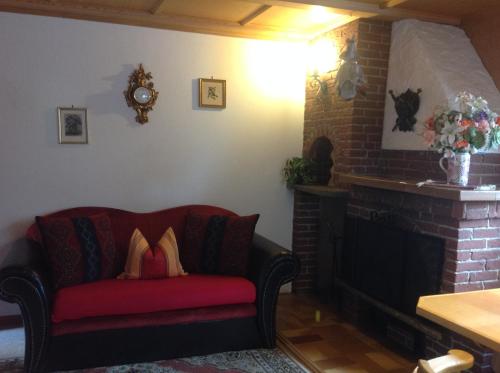 a red couch in a living room with a fireplace at Apartements Ingrid Unhoch-Raggl in Oberammergau