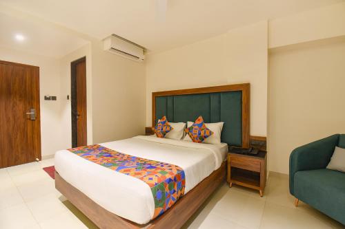 a bedroom with a large bed and a blue chair at FabHotel Shourya Regency in Jāmb