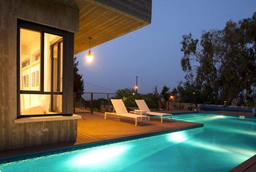 ein Swimmingpool mit zwei Liegestühlen neben einem Haus in der Unterkunft Villa Pnai in Rosch Pina