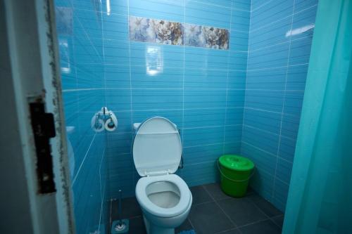a blue bathroom with a toilet and a green trash can at La Samurai House Assinie in Assinie