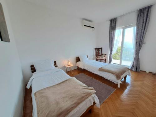 a bedroom with two beds and a large window at House Leana Herceg Novi in Herceg-Novi
