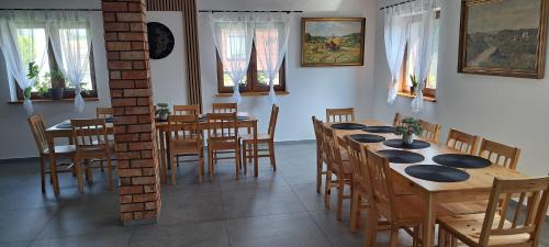 a dining room with wooden tables and chairs and windows at Pod Dachem Tykocin in Tykocin