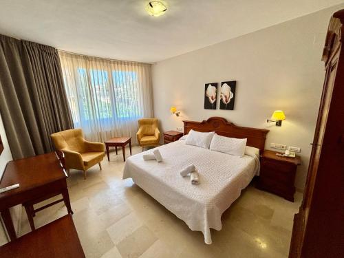 a hotel room with a bed and a chair at Aparthotel Bahia Pinosol in Jávea