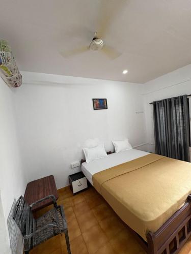 a bedroom with a large bed and a chair at Elowen Suites in Manjeri