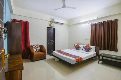 a bedroom with a bed and a chair in it at FabHotel Krishna Inn in Hinjewadi