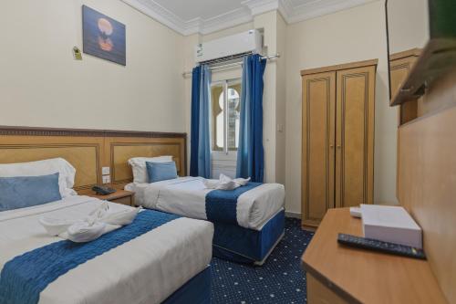 a hotel room with two beds and a desk at Wahet Al Deafah Hotel in Mecca