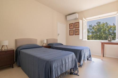 two beds in a white room with a window at Casale sul Mare - Grilli 2 in Lacona