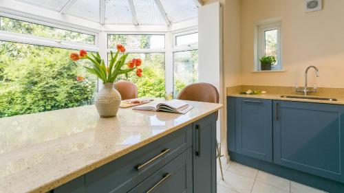 a kitchen with blue cabinets and a vase with flowers at Number eight in Beaumaris