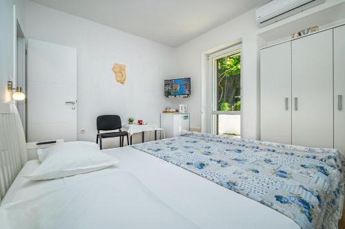 a white bedroom with a bed and a chair at Rooms Feme in Trogir