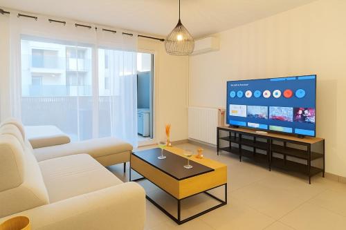 a living room with a couch and a tv at T3 moderne- Climatisé avec Parking & Terrasse à 5 min de Montpellier in Saint-Jean-de-Védas