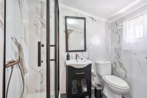 a white bathroom with a toilet and a sink at Casa El Mure in Ronda