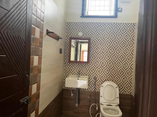 a bathroom with a toilet and a sink and a mirror at Solace in Coimbatore