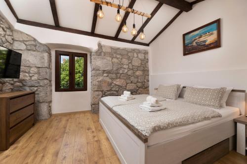 a bedroom with a bed and a stone wall at Villa Franka with heated pool in Milohnići