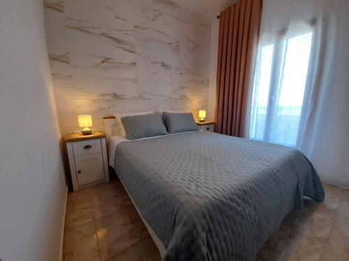 a bedroom with a bed and two night stands with lamps at ELEVER Apartments in Agia Marina