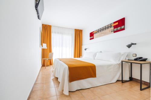 a hotel room with a white bed and a table at Hotel Miami Calella in Calella