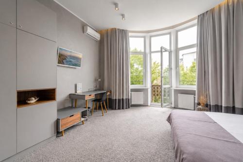 a bedroom with a bed and a desk and windows at Poet Art Hotel in Odesa