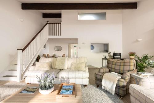 a living room with two couches and a staircase at Aintree Cottage in Cirencester