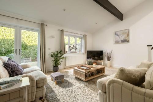 a living room with two couches and a tv at Aintree Cottage in Cirencester