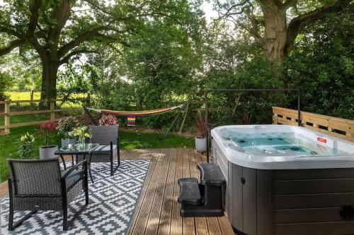 a hot tub on a deck with a table and chairs at Badgers Sett in Hankerton