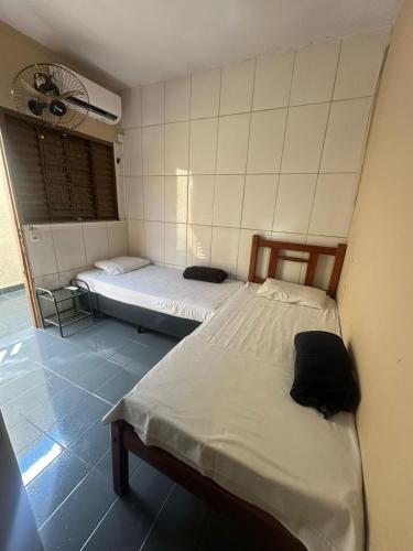 a room with two beds in a room with a fan at Cardoso Palace Hotel Ouro Verde in Rio Verde