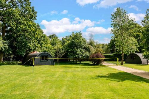 a net in the middle of a grass field with trees at Squirrels Drey in Hankerton
