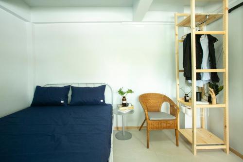 a bedroom with a blue bed and a chair at Uncle NID Hostel in Lat Krabang