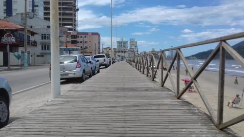 a wooden bridge over a beach with cars parked at Pousada Cama & Café in Navegantes