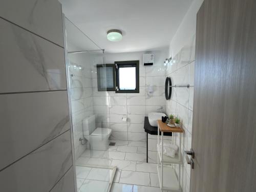 a white bathroom with a toilet and a sink at Freesia Grand Sea View Residence in Sarláta