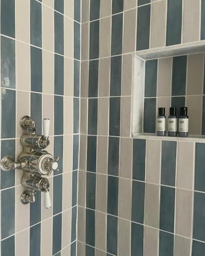 a bathroom with a shower with blue and white tiles at Stamping Cottage Studio Between St Ives & Penzance in Penzance