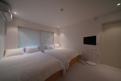 a bedroom with two beds and a flat screen tv at Covon Stay in Busan