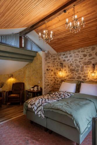 a bedroom with a bed and a stone wall at Domaine Le Verger Kleinschalige B&B met groot zwembad en buitenkeuken in Saint-Estèphe